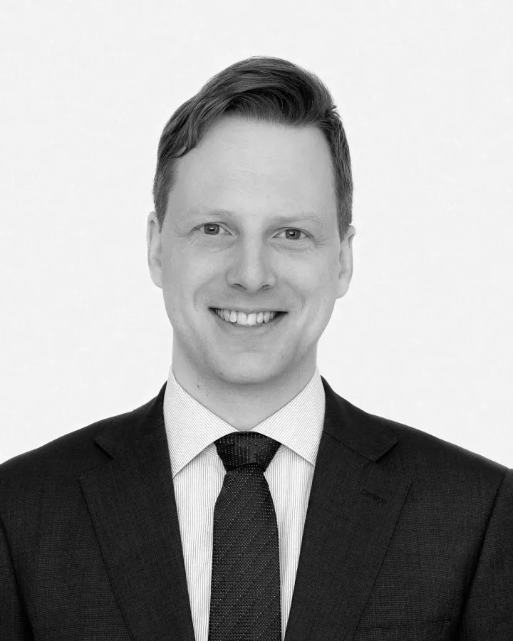 Sort-hvitt studioportrett av mann i dress og slips mot hvit bakgrunn
